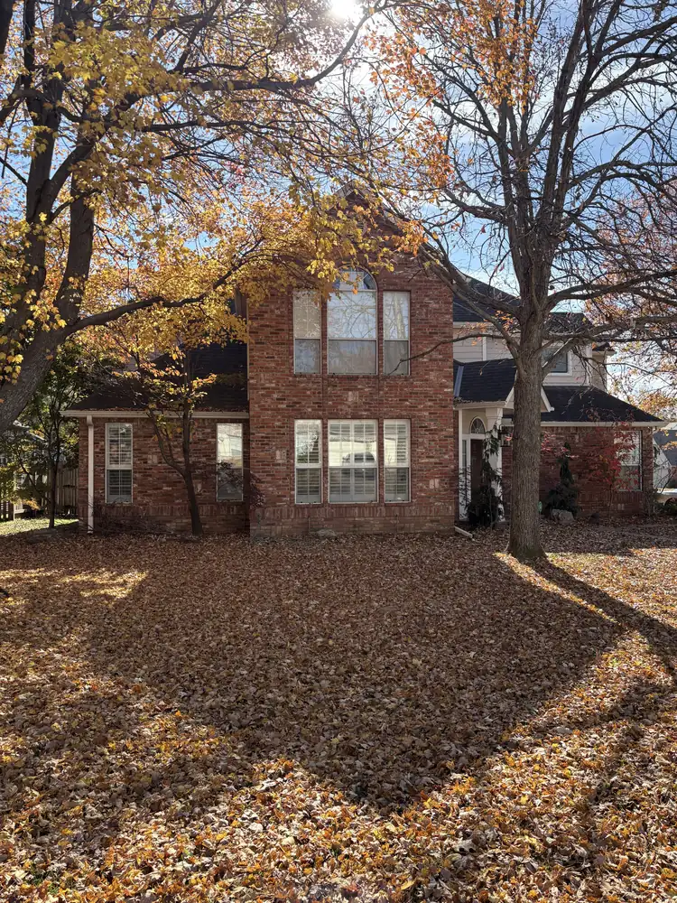 Older white windows on a red brick home before replacement